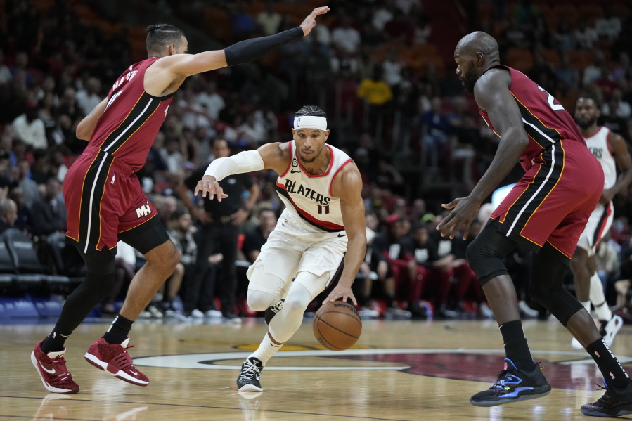 Portland Trail Blazers guard Josh Hart (11) drives to the basket against Miami Heat forward Caleb Martin, left, and center Dewayne Dedmon, right, during the first half of an NBA basketball game, Monday, Nov. 7, 2022, in Miami.