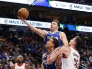 Dallas Mavericks guard Luka Doncic makes a layup next to center Dwight Powell and Portland Trail Blazers forward Drew Eubanks, right, during the first half of an NBA basketball game in Dallas, Saturday, Nov. 12, 2022.