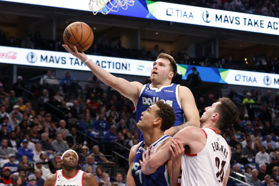 Dallas Mavericks guard Luka Doncic makes a layup next to center Dwight Powell and Portland Trail Blazers forward Drew Eubanks, right, during the first half of an NBA basketball game in Dallas, Saturday, Nov. 12, 2022.