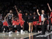 Portland Trail Blazers forward Jerami Grant (9) follows through on his 3-point shot as Brooklyn Nets forward Royce O'Neale (00) watches and the Trail Blazers bench reacts during the first half of an NBA basketball game Sunday, Nov. 27, 2022, in New York.