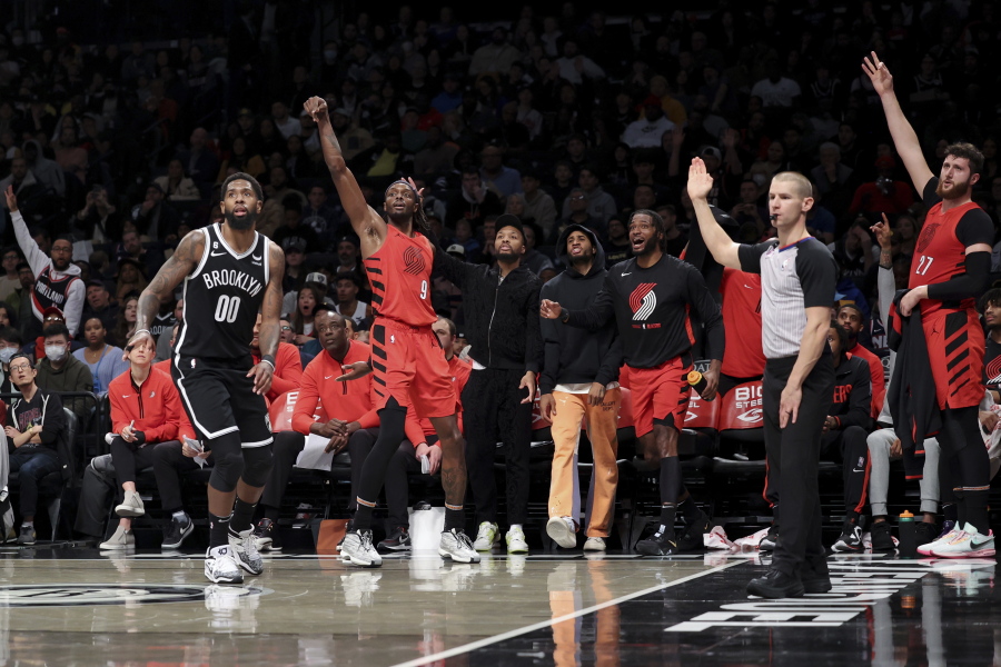 Portland Trail Blazers forward Jerami Grant (9) follows through on his 3-point shot as Brooklyn Nets forward Royce O'Neale (00) watches and the Trail Blazers bench reacts during the first half of an NBA basketball game Sunday, Nov. 27, 2022, in New York.