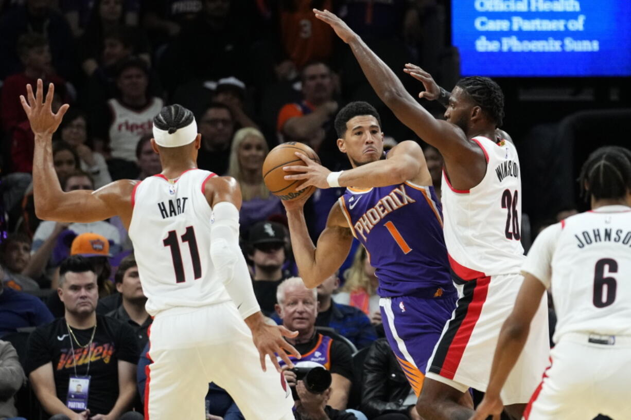 Phoenix Suns guard Devin Booker (1) looks to pass under pressure from Portland Trail Blazers forward Justise Winslow (26) during the first half of an NBA basketball game, Saturday, Nov. 5, 2022, in Phoenix.
