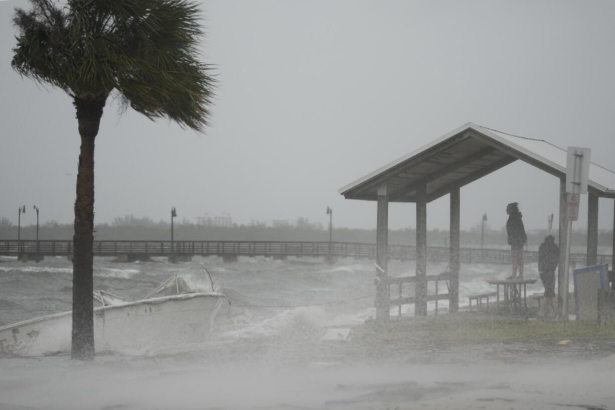 People brave rain and heavy winds to visit the waterfront along the Jensen Beach Causeway, as conditions deteriorate with the approach of Hurricane Nicole, Wednesday, Nov. 9, 2022, in Jensen Beach, Fla.