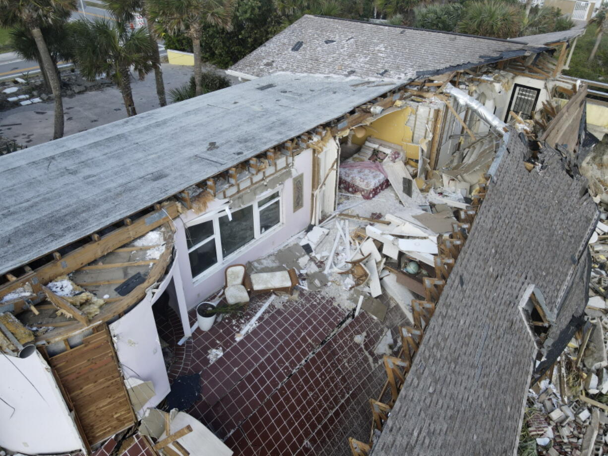 A bed and chairs are seen inside a home that half collapsed after the sand supporting it was swept away, following the passage of Hurricane Nicole, Saturday, Nov. 12, 2022, in Wilbur-By-The-Sea, Fla.