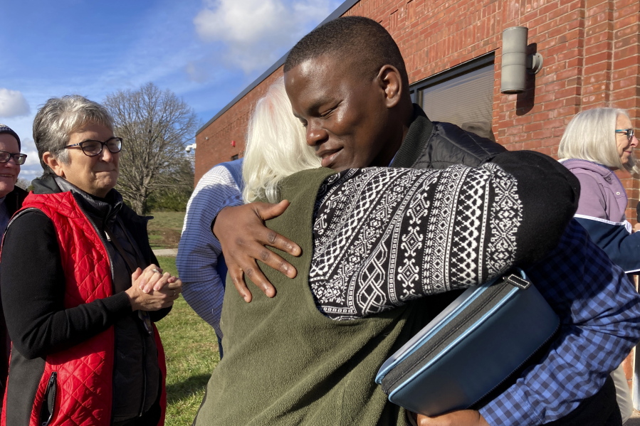 Ugandan refugee Steven Tendo, center top, hugs Dian Kahn, a member of the Central Vermont Refugee Action Network, outside a federal immigration office, in St. Albans, Vt., Tuesday, Nov. 15, 2022, after Tendo learned that his deportation has been delayed for a year. Tendo is an Ugandan activist who says he fears for his life if he were to be deported to his home country.