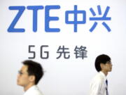 FILE - In this Sept. 26, 2018 file photo, visitors walk past a display from Chinese technology firm ZTE at the PT Expo in Beijing. The U.S. is banning the sale of communications equipment made by Chinese companies Huawei and ZTE and restricting the use of some China-made video surveillance systems, citing an "unacceptable risk" to national security. The 5-member Federal Communications Commission said Friday, Nov. 25, 2022 it has voted unanimously to adopt new rules that will block the importation or sale of certain technology products that pose security risks.