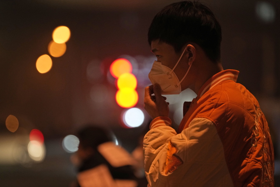 A man adjusts his mask on the street of Beijing, Sunday, Nov. 20, 2022. China on Sunday announced its first new death from COVID-19 in nearly half a year as strict new measures are imposed in Beijing and across the country to ward against new outbreaks.
