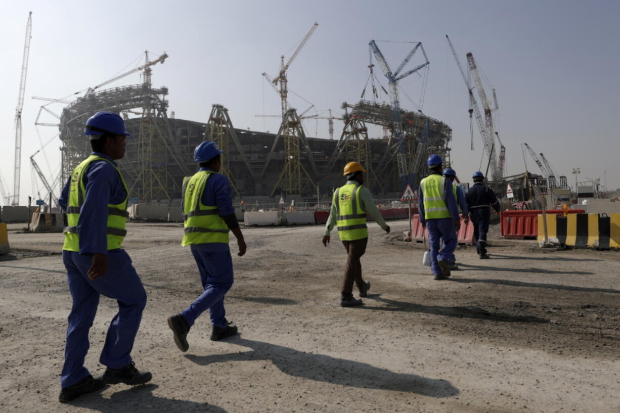 FILE - Workers walk to the Lusail Stadium, one of the 2022 World Cup stadiums, in Lusail, Qatar, Friday, Dec. 20, 2019. The eight stadiums for the World Cup, all within a 30-mile radius of Doha, are now largely complete. Migrant laborers who built Qatar's World Cup stadiums often worked long hours under harsh conditions and were subjected to discrimination, wage theft and other abuses as their employers evaded accountability, a rights group said in a report released Thursday.