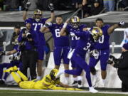 Washington wide receiver Taj Davis (3) eludes a tackle by Oregon defensive back Bennett Williams, bottom left, and heads to the end zone as teammates point the way during the second half of an NCAA college football game Saturday, Nov. 12, 2022, in Eugene, Ore.