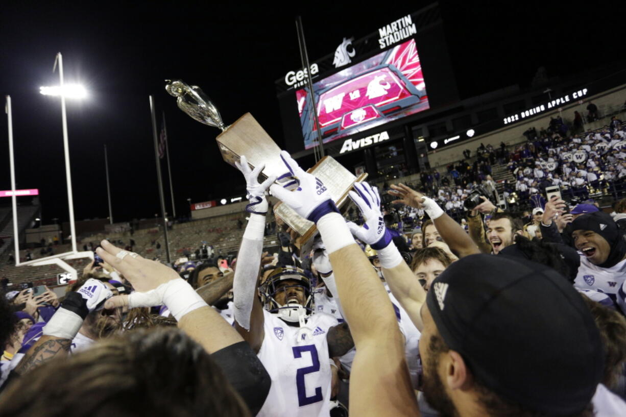 Washington players celebrate with the Apple Cup Trophy after their 51-33 win against Washington State on Saturday in Pullman.