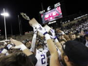 Washington players celebrate with the Apple Cup Trophy after their 51-33 win against Washington State on Saturday in Pullman.
