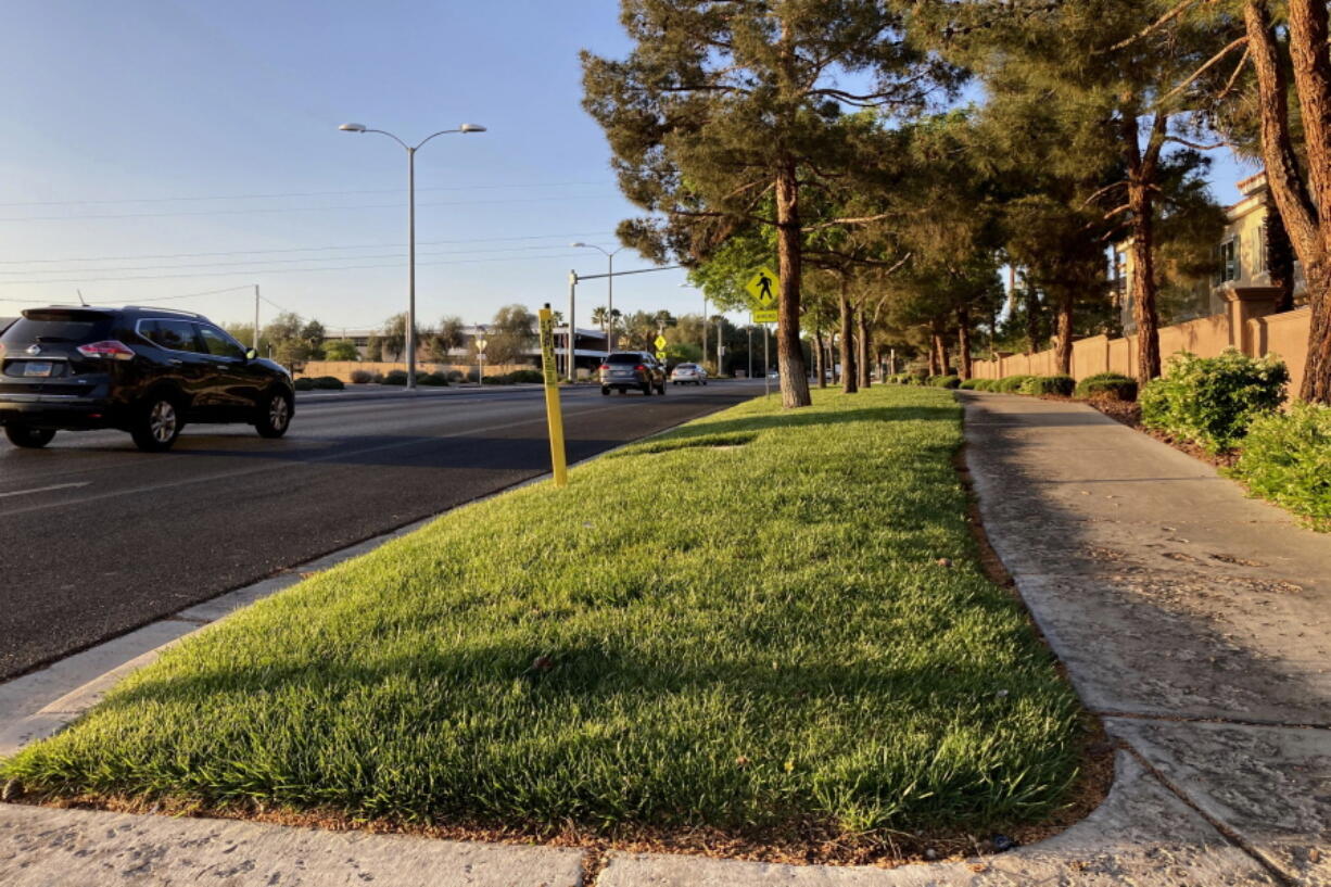 FILE - Traffic passes a grassy landscape on Green Valley Parkway in suburban Henderson, Nev., on April 9, 2021. In November 2022, some of the largest water agencies in the western United States agreed to a framework that would dramatically reduce the amount of decorative grass in cities such as Los Angeles, Las Vegas, Salt Lake City and Denver. The agreement comes as the seven states that rely on the overtapped Colorado River are facing a dire future with less water to go around.