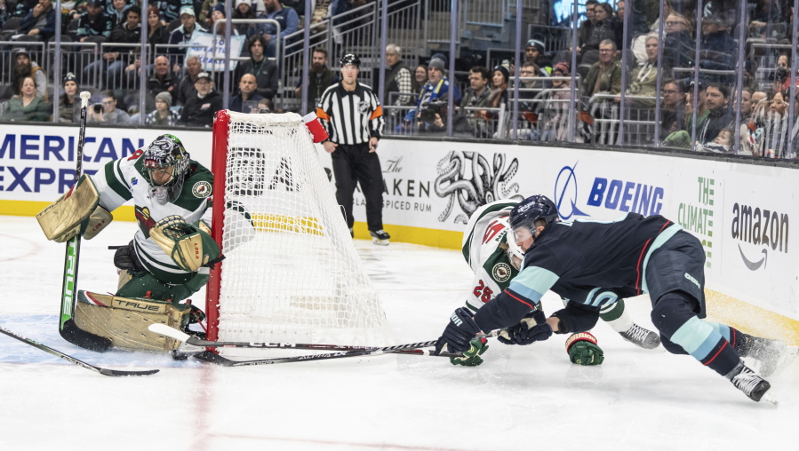 Minnesota Wild goalie Marc-Andre Fleury, left, knocks away a shot by Seattle Kraken forward Ryan Donato, right, during the second period of an NHL hockey game Friday, Nov. 11, 2022, in Seattle.