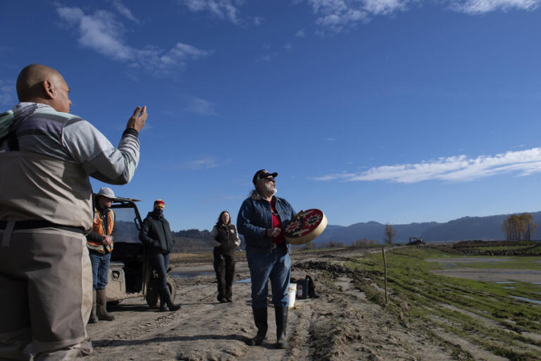 Sam Robinson, Chinook Indian Tribe vice chairman, center, and others perform the song "The Changer" before wapato planting at the rebuilt Steigerwald Lake National Wildlife Refuge in 2021.