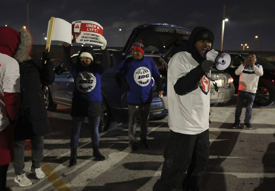 Steven Everett yells into a megaphone during a protest by ride-share drivers at a lot near O'Hare International Airport on Dec. 27, 2022. Drivers held a rally to bring attention to wage issues and deactivations without review. (John J.