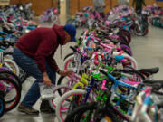 Pat Cotter of Vancouver, a Bike Clark County club member, puts the finishing touches on bicycles ready to go out Saturday during Waste Connections' Scott Campbell Christmas Promise.