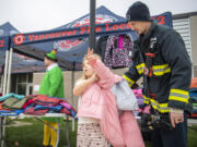 Vancouver firefighter Matt Hankins, right, helps Marshall Elementary second-grader Leilani Beck try on a coat at Marshall Elementary School. Members of Vancouver Fire Local 542 handed out donated coats to students who needed them.