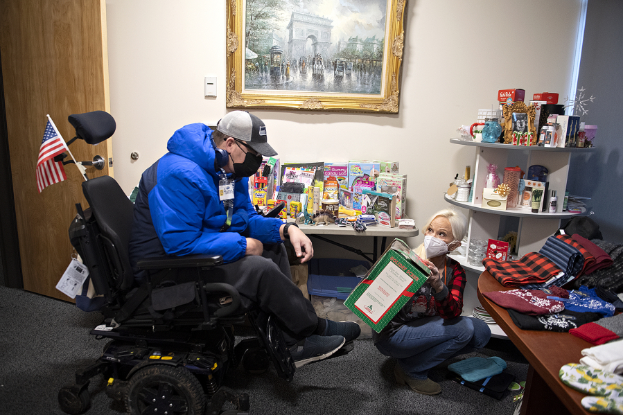 CDM Caregiving Services client Aaron Roth looks over the assortment of presents in the Christmas store with the help of volunteer Diana Schafer. The Christmas store is open for two weeks each December for CDM patients to do their Christmas shopping for free.