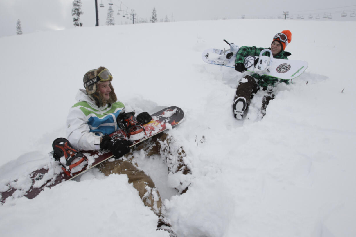 Ryan MacDonald, right, and Shane Anderson, both of Tacoma, rest with their snowboards after walking up a run in November 2010, at The Summit at Snoqualmie ski area.