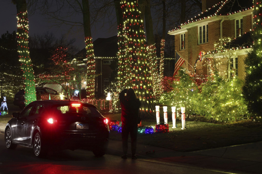 A woman takes a picture of a house decorated with holiday lights on Dec. 10 in Lincolnwood, Ill. (John J.