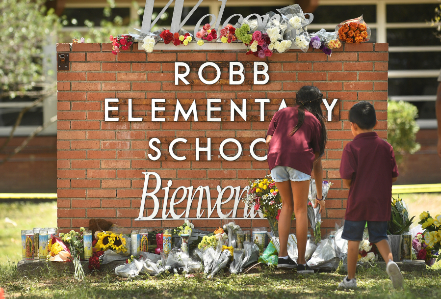 Family members who lost a sibling place flowers outside Robb Elementary School in Uvalde, Texas, on May 25, 2022. A day earlier, an 18-year-old gunman entered the school and killed 19 children and two teachers.