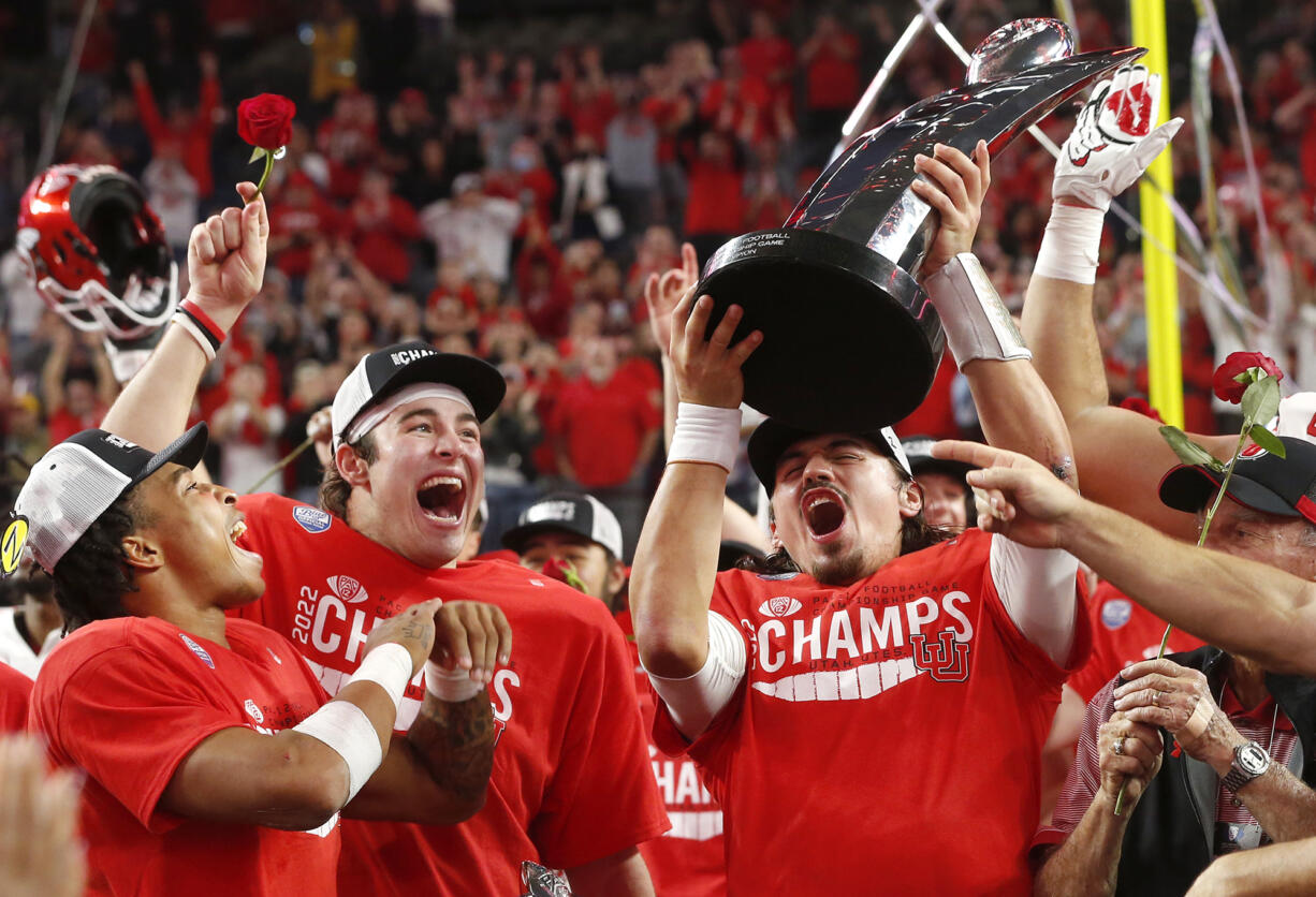 Utah quarterback Cameron Rising, right, holds up the trophy and celebrates with Dalton Kincaid, center, and Micah Bernard after Utah defeated Southern California 47-24 in the Pac-12 Conference championship NCAA college football game Friday, Dec. 2, 2022, in Las Vegas.