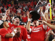 Utah quarterback Cameron Rising, right, holds up the trophy and celebrates with Dalton Kincaid, center, and Micah Bernard after Utah defeated Southern California 47-24 in the Pac-12 Conference championship NCAA college football game Friday, Dec. 2, 2022, in Las Vegas.