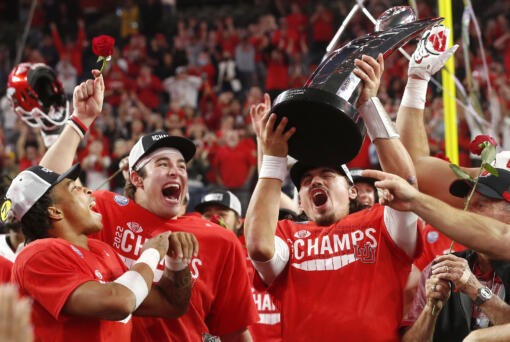 Utah quarterback Cameron Rising, right, holds up the trophy and celebrates with Dalton Kincaid, center, and Micah Bernard after Utah defeated Southern California 47-24 in the Pac-12 Conference championship NCAA college football game Friday, Dec. 2, 2022, in Las Vegas. (AP Photo/Steve Marcus)