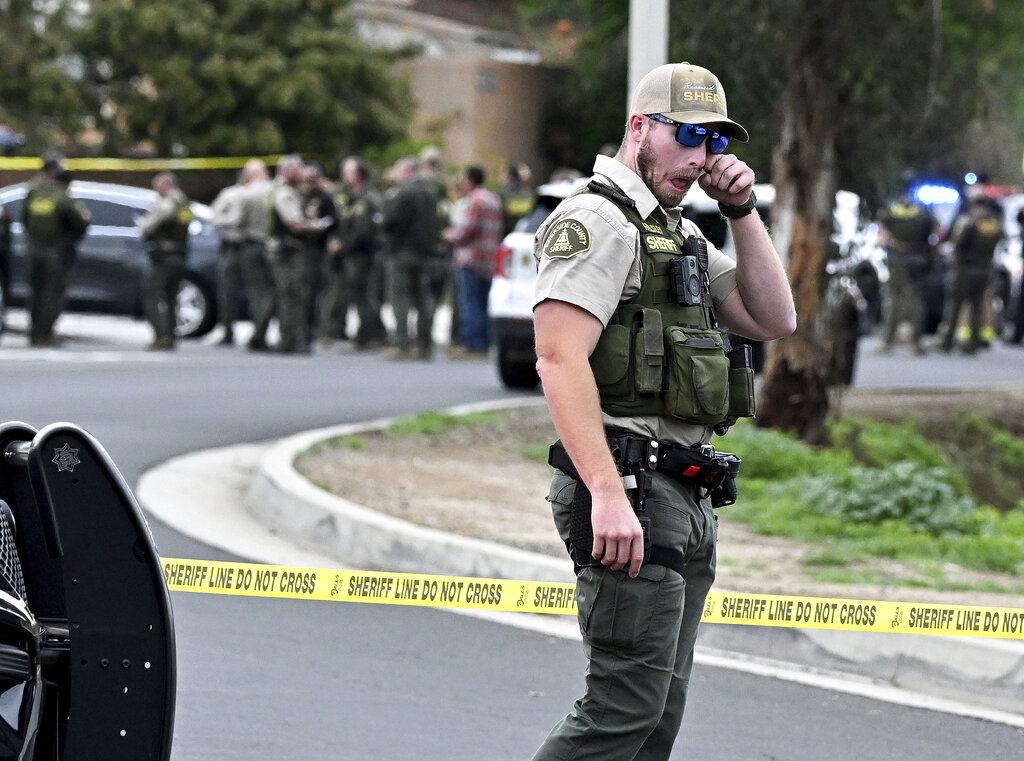 A Riverside County Sheriff's deputy wipes his eye as he stands near the corner of Golden West Ave. and Condor Drive  in Jurupa Valley, Calif. Thursday, Dec. 29, 2022. Authorities say a Southern California sheriff’s deputy has been shot during a traffic stop.