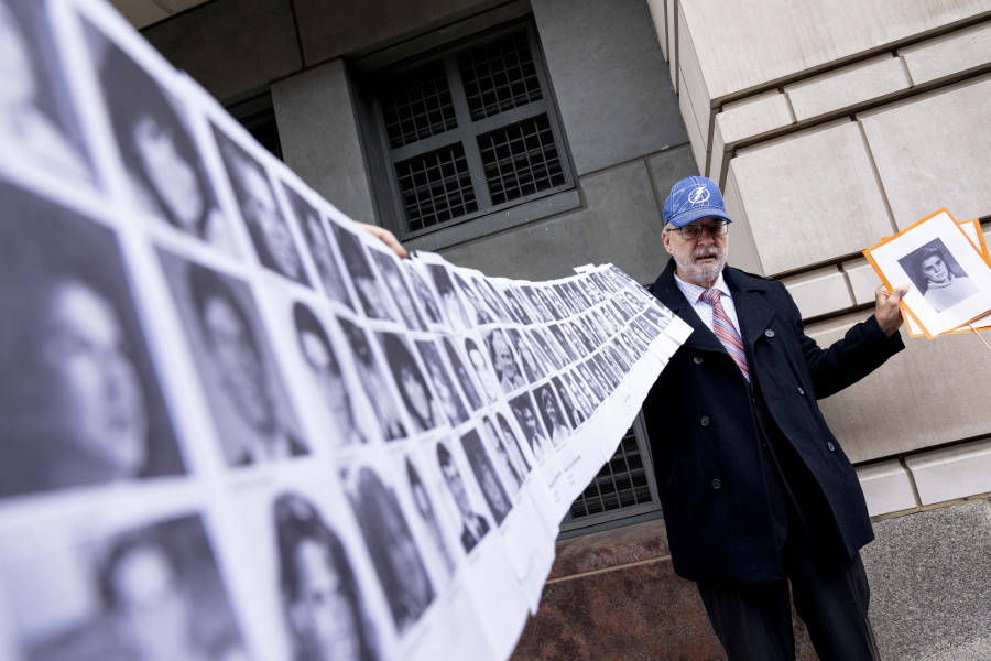 Paul Hudson of Sarasota, Fla., holds up a photo of his daughter Melina who was killed at 16 years old along with the photos of almost a hundred other victims of the bombing of Pan Am Flight 103 over Lockerbie, Scotland, as he speaks to members of the media in front of the federal courthouse in Washington, Monday, Dec. 12, 2022. The Justice Department says a Libyan intelligence official, Abu Agila Mohammad Mas'ud Kheir Al-Marimi, accused of making the bomb that brought down Pan Am Flight 103 over Lockerbie, Scotland, in 1988 in an international act of terrorism has been taken into U.S. custody and will face federal charges in Washington.