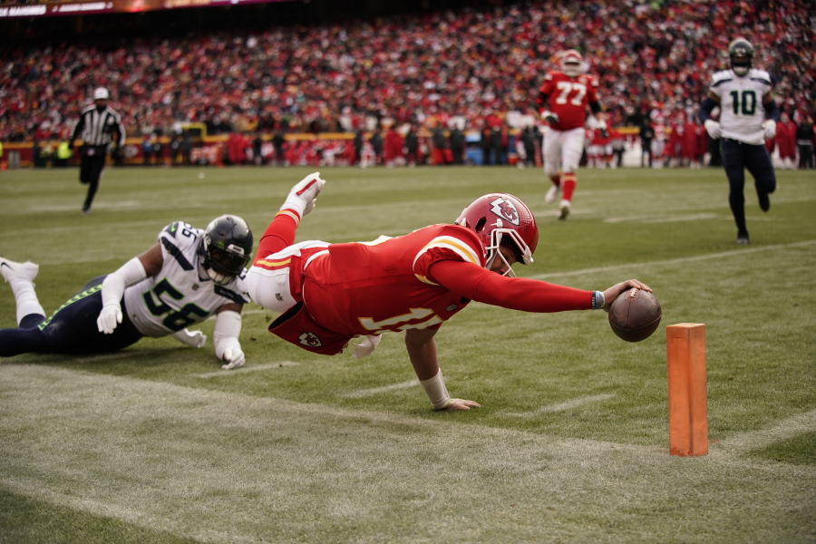 Kansas City Chiefs quarterback Patrick Mahomes (15) dives for the end zone pylon to score a touchdown as Seattle Seahawks linebacker Jordyn Brooks (56) defends during the second half of an NFL football game Saturday, Dec. 24, 2022, in Kansas City, Mo.