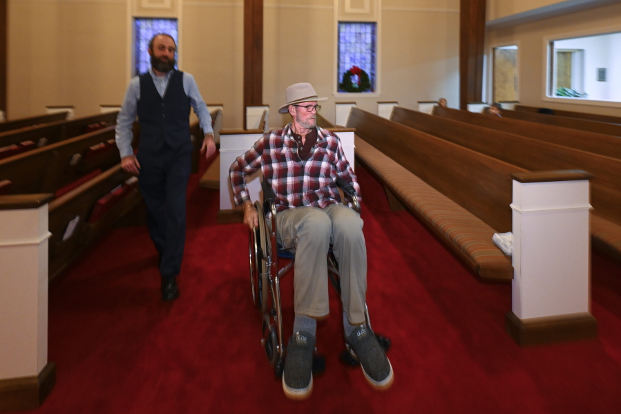 Jerry Lamb, who suffers from a spine condition, talks to Pastor Adam Kelchner at Camden First United Methodist Church Thursday, Dec. 8, 2022, in Camden, Tenn. The church at the urging of the pastor recently had a couple pews cut in half so Jerry, and anyone else who uses a wheelchair, walker or other aid, can still sit with the rest of the congregation.