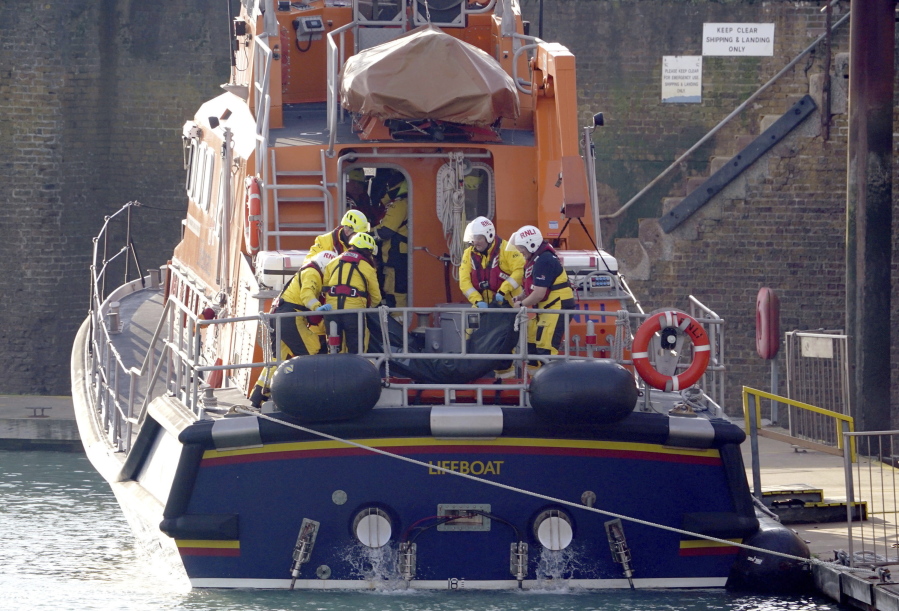 Members of the Dover lifeboat place a body bag on a stretcher after returning to the Port of Dover after a large search and rescue operation launched in the Channel off the coast of Dungeness, in Kent, Wednesday Dec. 14, 2022, following an incident involving a small boat likely to have been carrying migrants. Helicopters and lifeboats have been dispatched to the English Channel off the coast of Kent in southern England to rescue a small boat in distress, authorities said Wednesday.