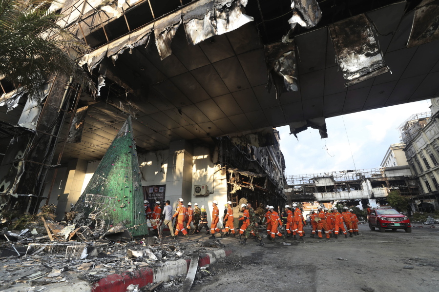 Cambodian and Thai rescue experts walk through a ruined building for a searching operation at the scene of a massive fire at a Cambodian hotel casino in Poipet, west of Phnom Penh, Cambodia, Friday, Dec. 30, 2022. The fire at the Grand Diamond City casino and hotel Thursday injured over 60 people and killed more than a dozen, a number that officials warned would rise after the search for bodies resumes Friday.