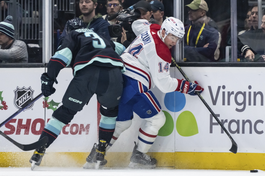 Seattle Kraken defenseman Will Borgen, left, checks Montreal Canadiens forward Nick Suzuki against the boards during the second period of an NHL hockey game Tuesday, Dec. 6, 2022, in Seattle.