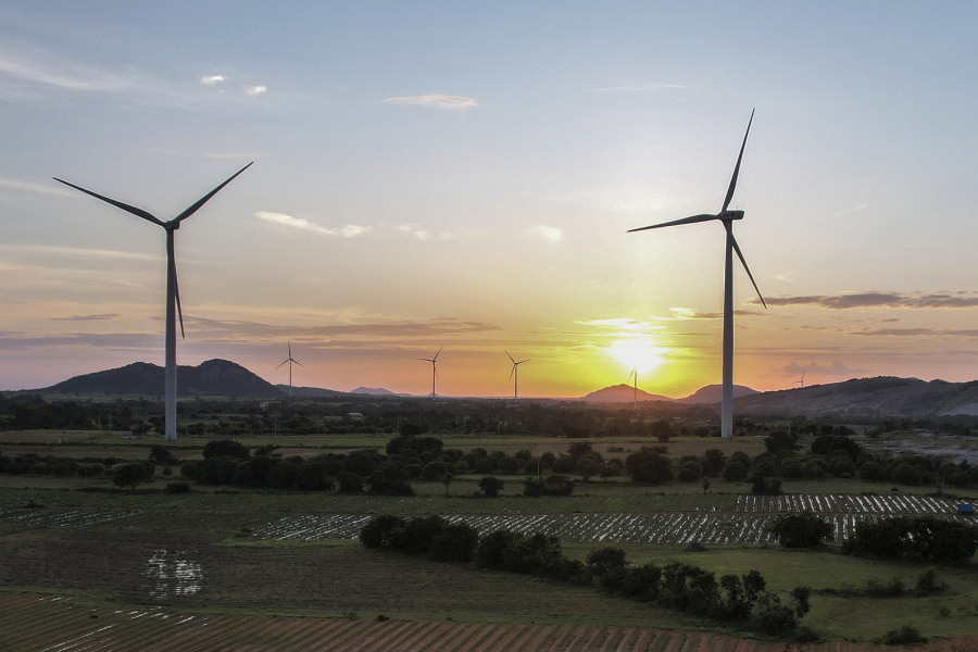 FILE - The sun sets behind a windmill farm in Anantapur district, Andhra Pradesh, India, Sept 14, 2022. India officially takes up its role as chair of the Group of 20 leading economies for the coming year Thursday, Dec. 1 and it's putting climate at the top of the group's priorities.