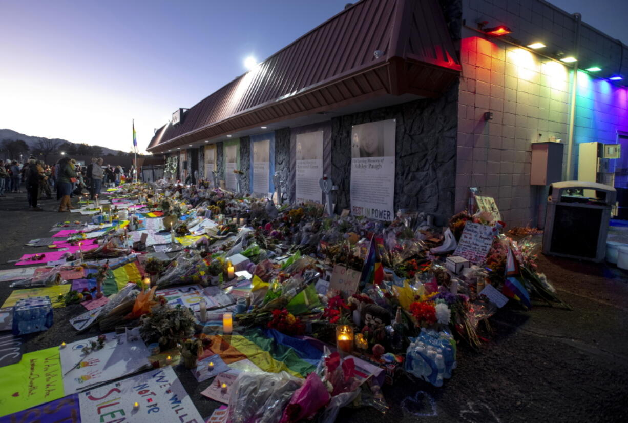 File - Mourners gather outside Club Q to visit a memorial, which has been moved from a sidewalk outside of police tape that was surrounding the club, on Friday, Nov. 25, 2022, in Colorado Spring, Colo. The suspect accused of entering the gay nightclub clad in body armor and opening fire with an AR-15-style rifle, killing five people and wounding 17 others, is set to appear in court again Tuesday, Dec. 6 to learn what charges prosecutors will pursue in the attack, including possible hate crime counts.