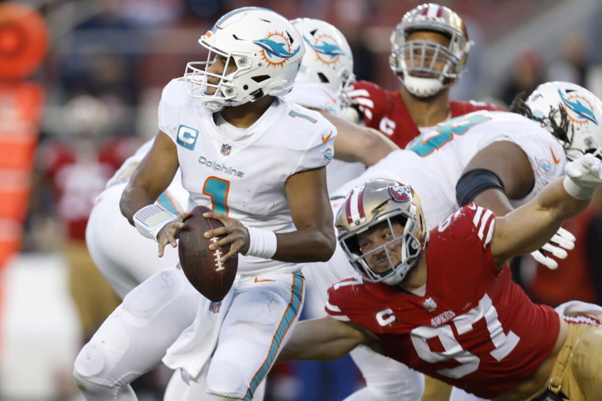 Miami Dolphins quarterback Tua Tagovailoa (1) looks to pass before San Francisco 49ers defensive end Nick Bosa (97) caused Tagovailoa to fumble, which 49ers linebacker Dre Greenlaw returned for a touchdown, during the second half of an NFL football game in Santa Clara, Calif., Sunday, Dec. 4, 2022.