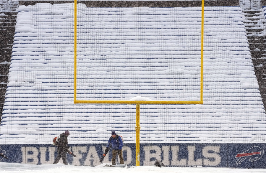 Grounds crew work to clear snow off the field at Highmark Stadium before an NFL football game between the Buffalo Bills and the Miami Dolphins in Orchard Park, N.Y., Saturday, Dec. 17, 2022. (AP Photo/Gene J.