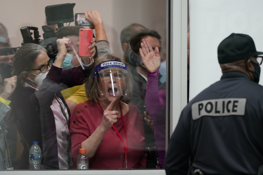 FILE - Election challengers yell as they look through the windows of the central counting board as police were helping to keep additional challengers from entering due to overcrowding, in Detroit, Nov. 4, 2020.