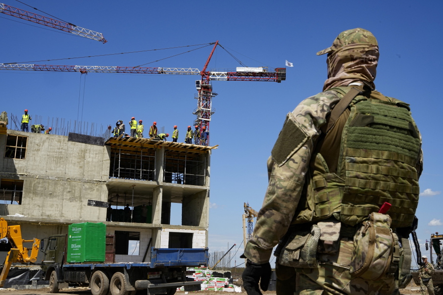 FILE - A Russian soldier guards the site of a new apartment building which is is being built with the support of the Russian Defense Ministry, in Mariupol, in territory under control of the government of the Donetsk People's Republic, in eastern Ukraine, Wednesday, July 13, 2022. This photo was taken during a trip organized by the Russian Ministry of Defense.
