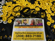 A flyer seeking information about the killings of four University of Idaho students who were found dead on Nov. 13, 2022, is displayed on a table along with buttons and bracelets, Wednesday, Nov. 30 during a vigil in memory of the victims in Moscow, Idaho. (AP Photo/Ted S.