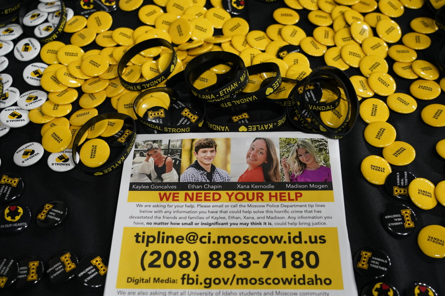 A flyer seeking information about the killings of four University of Idaho students who were found dead on Nov. 13, 2022, is displayed on a table along with buttons and bracelets, Wednesday, Nov. 30 during a vigil in memory of the victims in Moscow, Idaho. (AP Photo/Ted S.