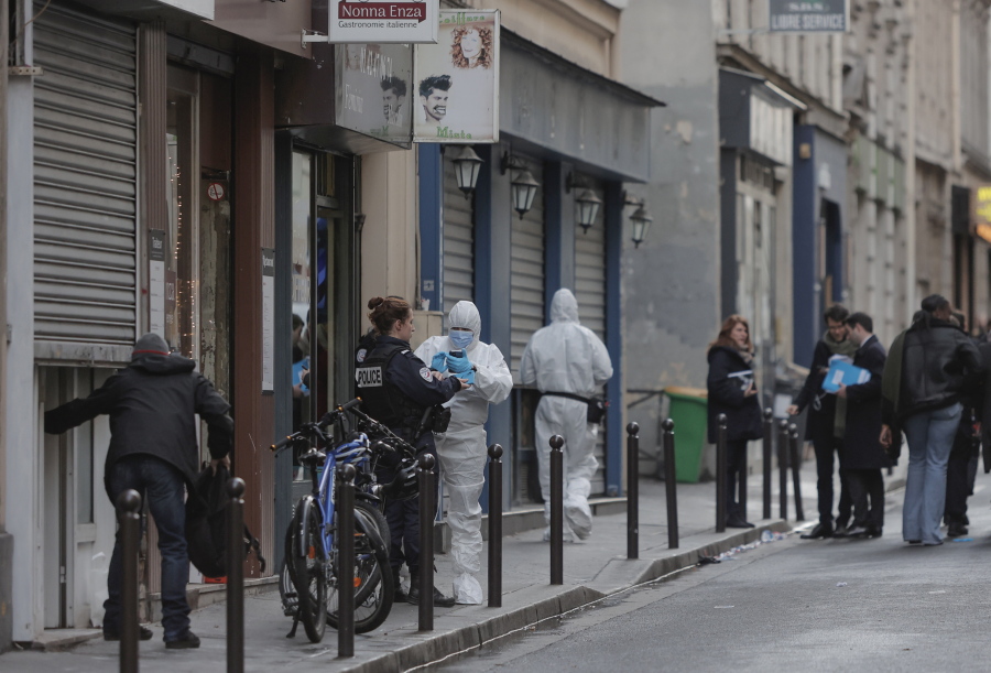 Police investigate at the scene where a shooting took place in Paris, Friday, Dec. 23, 2022. A shooting targeting a Kurdish cultural center in a bustling Paris neighbourhood Friday left three people dead and three others wounded, authorities said. A 69-year-old suspect was wounded and arrested..