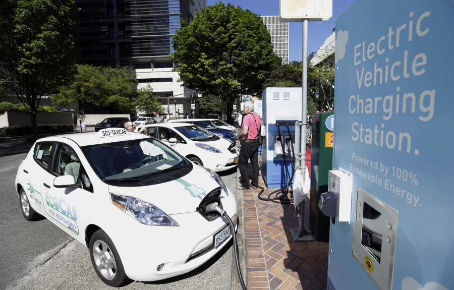 FILE - A line of electric cars and newly installed charging stations sit in front of the Portland General Electric headquarters building on July 28, 2015, in Portland, Ore. Policymakers for the Oregon Department of Environmental Quality on Monday, Dec. 19, 2022, approved a rule that prohibits the sale of new gasoline-powered passenger vehicles in Oregon by 2035.