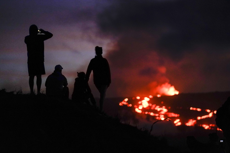 FILE - People watch lava from the Mauna Loa volcano Thursday, Dec. 1, 2022, near Hilo, Hawaii. U.S. scientists declared Tuesday, Dec. 13, 2022, that two active Hawaii volcanoes -- one where lava destroyed hundreds of homes in 2018 and another where lava recently stalled before reaching a crucial Big Island highway -- have stopped erupting.