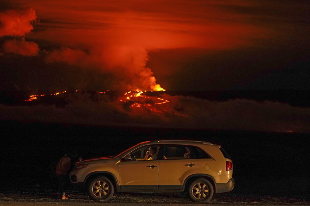 FILE - A man talks on a phone in his car alongside Saddle Road as the Mauna Loa volcano erupts Wednesday, Nov. 30, 2022, near Hilo, Hawaii.  (AP Photo/Gregory Bull, File) (U.S.