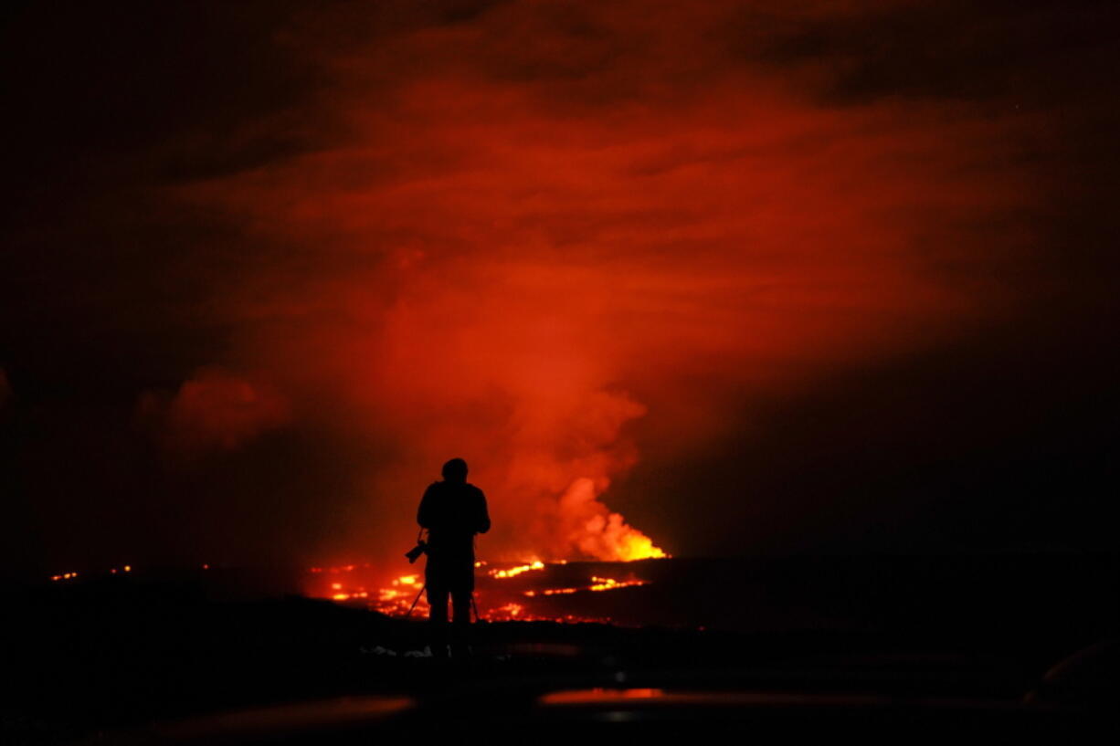 A photographer takes pictures of the Mauna Loa volcano as it erupts Wednesday, Nov. 30, 2022, near Hilo, Hawaii.
