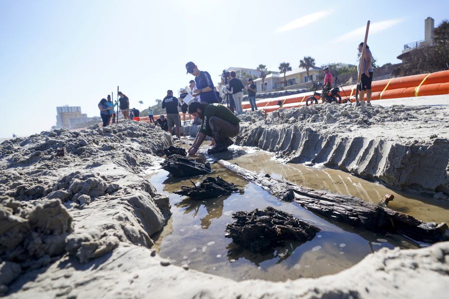 Archaeologists study a wooden structure in the sand on Tuesday in Daytona Beach, Fla. Severe beach erosion caused by two late-season hurricanes helped partially uncover what appears to be part of an 80-foot-long ship in the sand on Daytona Beach Shores, officials said.