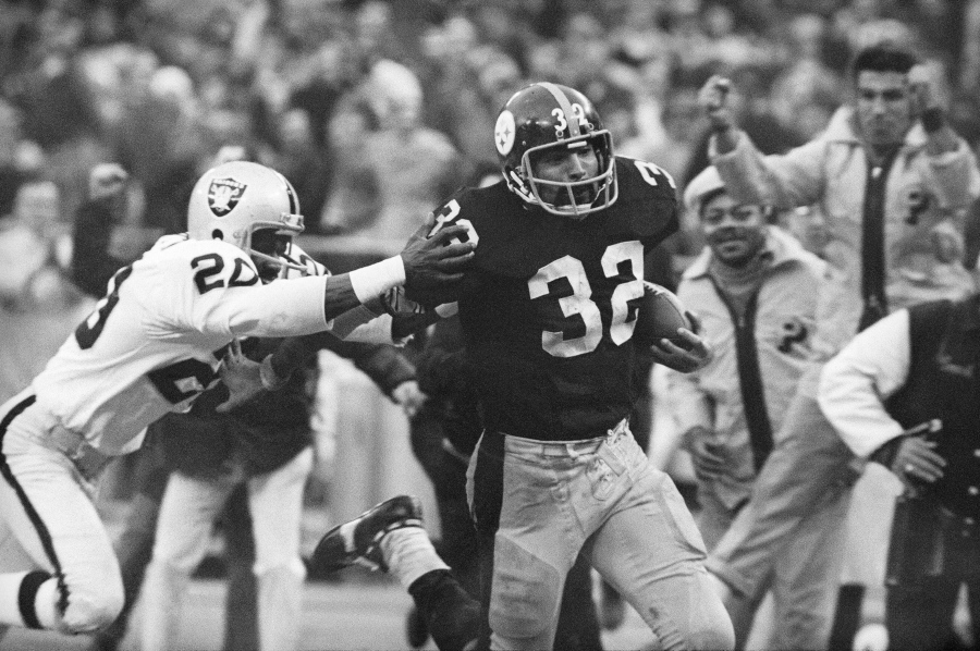 FILE - Pittsburgh Steelers' Franco Harris (32) eludes a tackle by Oakland Raiders' Jimmy Warren as he runs 42-yards for a touchdown after catching a deflected pass during an AFC Divisional NFL football playoff game in Pittsburgh, Dec. 23, 1972. Harris' scoop of a deflected pass and subsequent run for the winning touchdown -- forever known as the "Immaculate Reception" -- has been voted the greatest play in NFL history. On the 50th anniversary of the "Immaculate Reception" -- Friday, Dec. 23, 2022 -- Pittsburghers recall how it boosted morale during the collapse of the steel industry and has served as a cultural rallying point ever since.